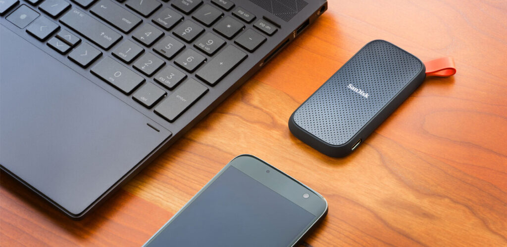 SanDisk Portable SSD 1TB วางข้างแล็ปท็อปสำหรับสำรองข้อมูล MacBook ด้วย Time Machine